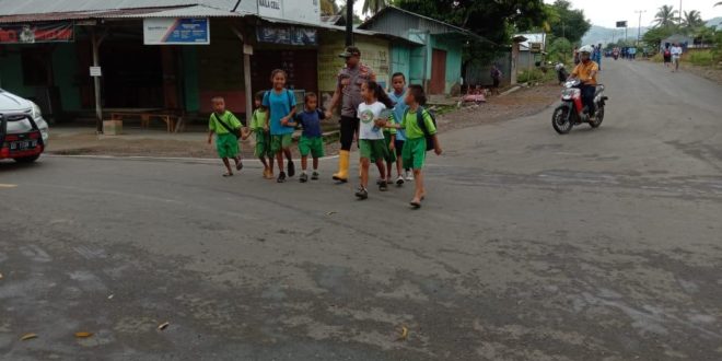 Kapolsek Komodo Bantu Menyembrangi Siswa SD yang Hendak Pergi ke Sekolah